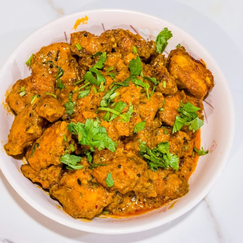 Close-up of a bowl of chicken curry, garnished with fresh cilantro.